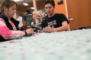 Two students tying the ends of a blanket